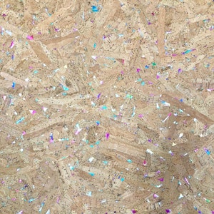 May include: A close-up of a cork board with a variety of colorful glitter embedded in the surface.