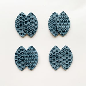 May include: Four pairs of teal blue faux leather earrings with a hexagonal pattern. The earrings are shaped like a leaf.