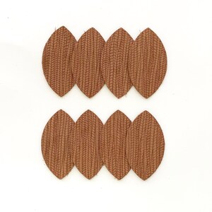May include: Eight brown leather leaf shapes with a textured surface. The leaves are arranged in two rows of four.