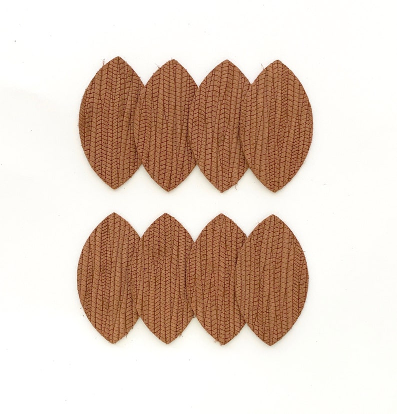 May include: Eight brown leather leaf shapes with a textured surface. The leaves are arranged in two rows of four.