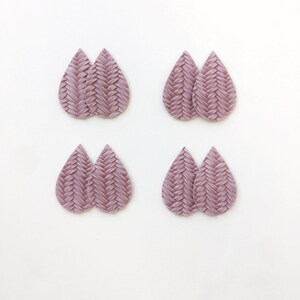 May include: Four pairs of mauve teardrop earrings with a woven texture are displayed against a white backdrop. The earrings are evenly spaced, highlighting their intricate design and colour.