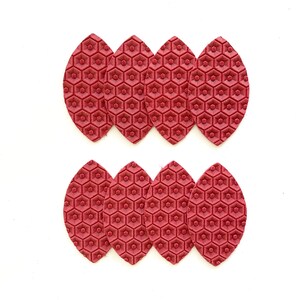 May include: Twelve red leather leaves with a hexagonal pattern. The leaves are arranged in two rows of six.