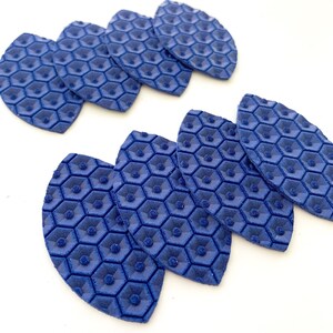 May include: Seven blue, leaf-shaped, textured fabric patches with a honeycomb pattern. The patches are arranged in a staggered pattern.