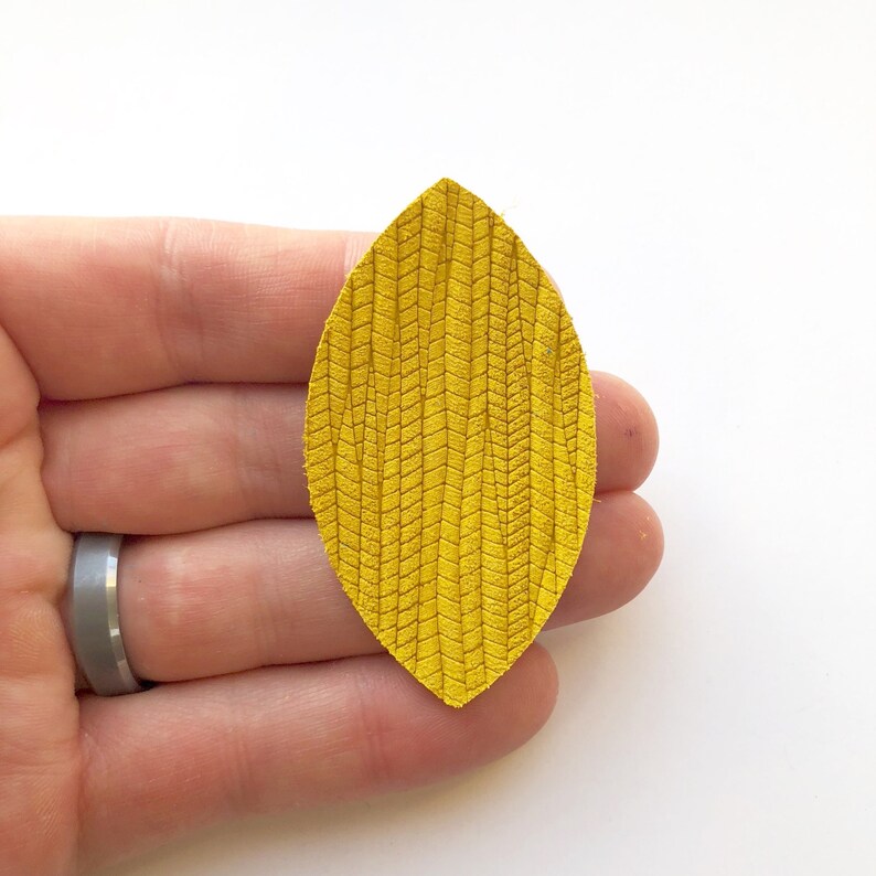 May include: A yellow leather leaf with a textured pattern. The leaf is approximately 5 cm long and 2.5 cm wide.