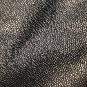 May include: Close-up of a dark gray leather texture with a pebbled surface.