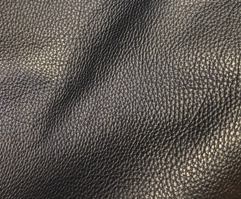 May include: Close-up of a dark gray leather texture with a pebbled surface.