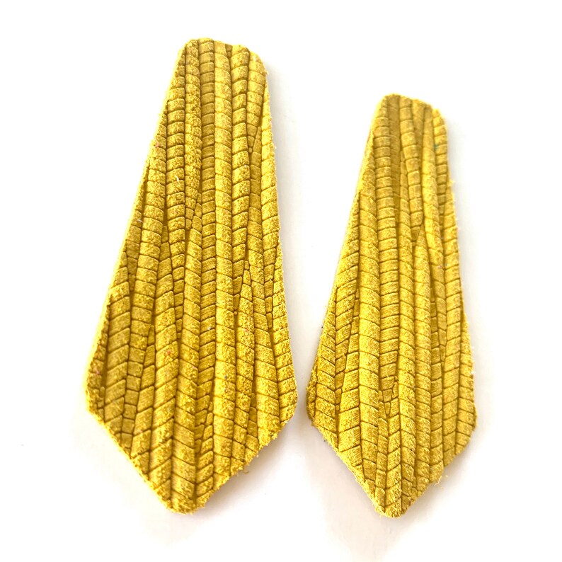 Puede incluir: Un par de pendientes de ante amarillo con un patr&oacute;n de chevron texturizado.
