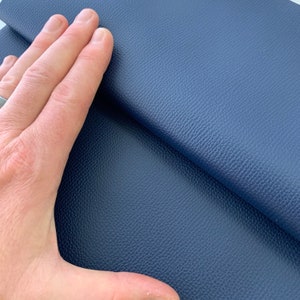 May include: Close-up of a dark blue textured fabric. The fabric has a pebbled surface and a soft, supple feel.