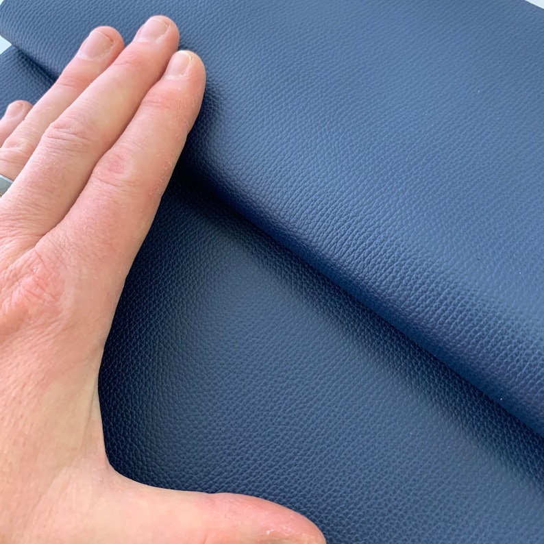 May include: Close-up of a dark blue textured fabric. The fabric has a pebbled surface and a soft, supple feel.