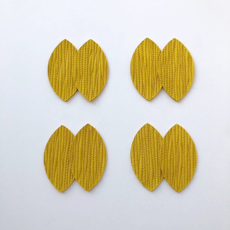 May include: Four pairs of yellow leather earrings shaped like leaves. Each pair is made of two leaves that are joined together at the centre.