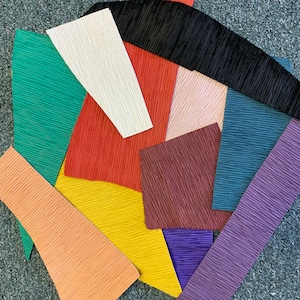 May include: A collection of fabric swatches in various colors and textures, including green, red, pink, purple, blue, yellow, and black.
