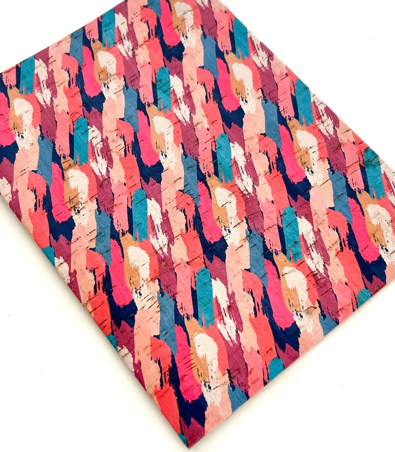 May include: A sheet of cork fabric with a colorful abstract brushstroke pattern. The pattern features shades of pink, red, blue, teal, and beige.