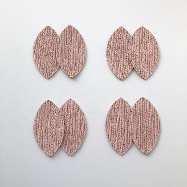 May include: Four pairs of pink leather earrings in the shape of a leaf. Each earring is made of two pieces of leather that are sewn together.