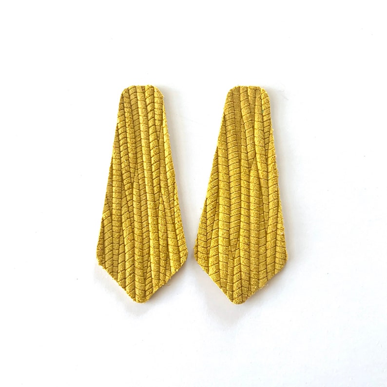 Puede incluir: Un par de pendientes de ante amarillo con un dise&ntilde;o texturizado y tejido. Los pendientes tienen forma de l&aacute;grima.