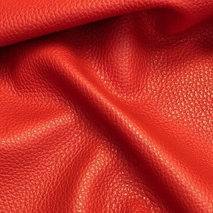 May include: Close-up of a bright red leather fabric with a textured surface.