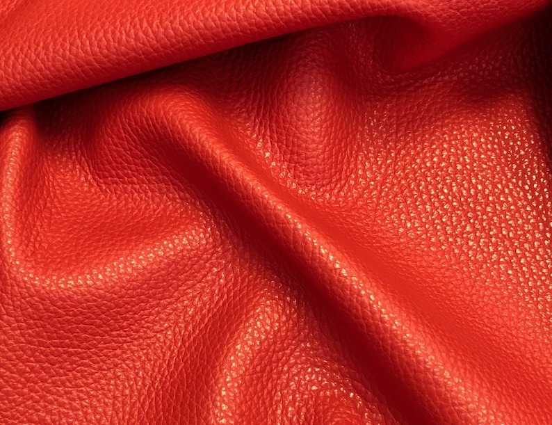 May include: Close-up of a bright red leather fabric with a textured surface.