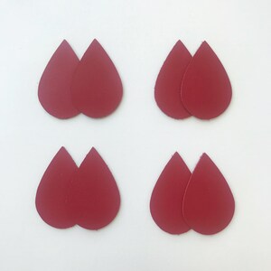 Pu&ograve; includere: Quattro paia di orecchini a goccia in pelle rossa. Gli orecchini sono lunghi circa 5 cm.