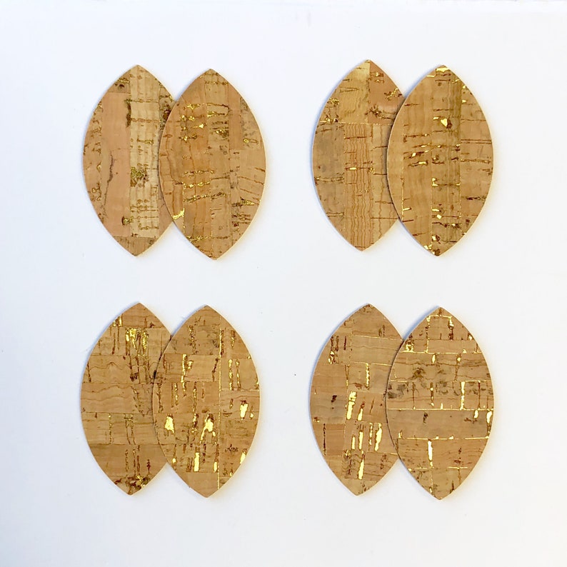 May include: Four pairs of cork leaf-shaped earrings with gold accents. Each pair is made of two pieces of cork, one with a more pronounced gold pattern than the other.
