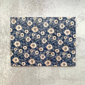 May include: A cork board with a blue and white floral pattern. The cork board is rectangular and has a natural cork texture.