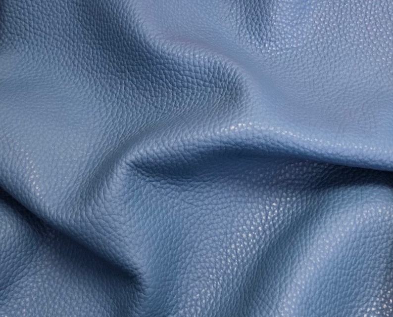 May include: Close-up of a textured blue leather fabric. The leather has a pebbled surface and a soft, supple feel.
