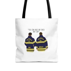 May include: White tote bag with a black handle and a graphic of two firefighters with the text "YOU CAN HAVE MY BACK ANY DAY" and "LOS ANGELES F.D." on their jackets. The firefighters are wearing blue jackets with yellow stripes and have the names "DIAZ" and "BUCKLEY" on their jackets.