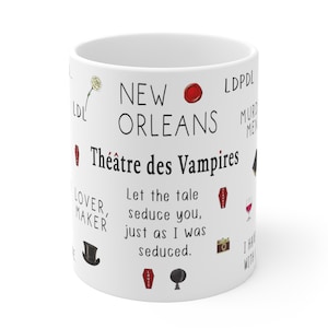 K&ouml;nnte beinhalten: Wei&szlig;er Keramikbecher mit den W&ouml;rtern "New Orleans" und "Th&eacute;&acirc;tre des Vampires" in Schwarz bedruckt. Der Becher zeigt verschiedene Illustrationen, darunter einen Sarg, einen Zylinder und eine Kamera. Der Text auf dem Becher lautet "Let the tale seduce you, just as I was seduced."