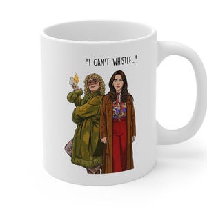 May include: White ceramic mug featuring an illustration of two women in vintage clothing. One woman holds a lit match, and the mug has the text "I CAN'T WHISTLE..." printed on it. The women are wearing coats and dresses.