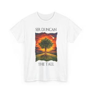 May include: White t-shirt featuring a colorful illustration of a tree with a sunset background. The text "SER DUNCAN THE TALL" is printed above and below the image. The shirt is made of a soft, comfortable material.