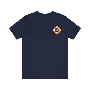May include: A navy blue t-shirt with a yellow and red firefighter emblem on the left chest.