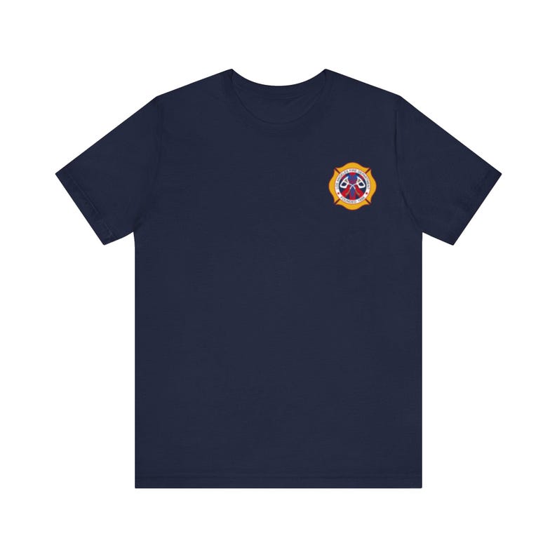 May include: A navy blue t-shirt with a yellow and red firefighter emblem on the left chest.