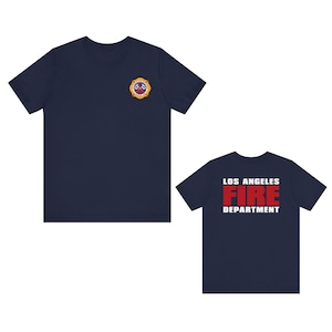 May include: Two navy blue t-shirts with the Los Angeles Fire Department logo. One shirt has the logo on the front and the other has the logo on the back.