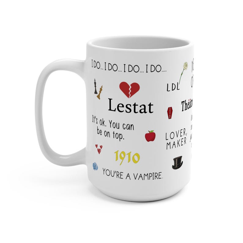 K&ouml;nnte beinhalten: Wei&szlig;e Keramiktasse mit dem Wort "Lestat" und weiteren Texten und Grafiken. Die Tasse hat einen Griff auf der linken Seite und ist mit einem zerbrochenen Herzen, einem Apfel und einem Zylinder verziert. Der Text enth&auml;lt "1910" und "You're a Vampire."