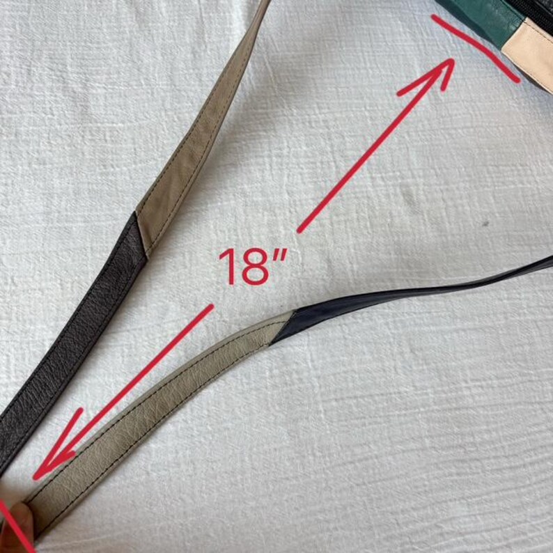 May include: A close-up of a purse strap, measuring 18 inches. The strap is made of leather in shades of black, tan, and cream. The purse itself is visible in the upper right corner, with green, black, and cream panels.