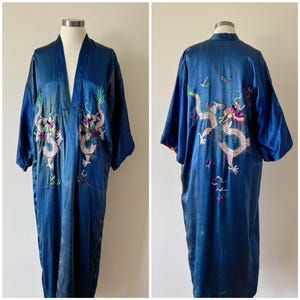 May include: A long, flowing blue robe with embroidered dragon designs in white, pink, green, and purple. The robe is made of a shiny, silky material and has wide sleeves. The robe is displayed on a mannequin.