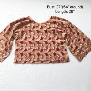 May include: A tan and burgundy patterned top with wide sleeves. The top has a round neckline and a repeating fan-like design. The bust measures 27 inches (54 inches around), and the length is 26 inches.