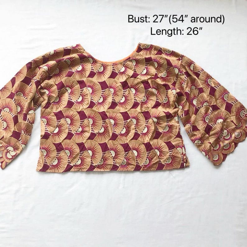 May include: A tan and burgundy patterned top with wide sleeves. The top has a round neckline and a repeating fan-like design. The bust measures 27 inches (54 inches around), and the length is 26 inches.