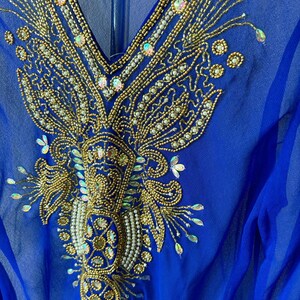 May include: A royal blue sheer top with a gold and white beaded design. The design features intricate floral patterns and sequins.
