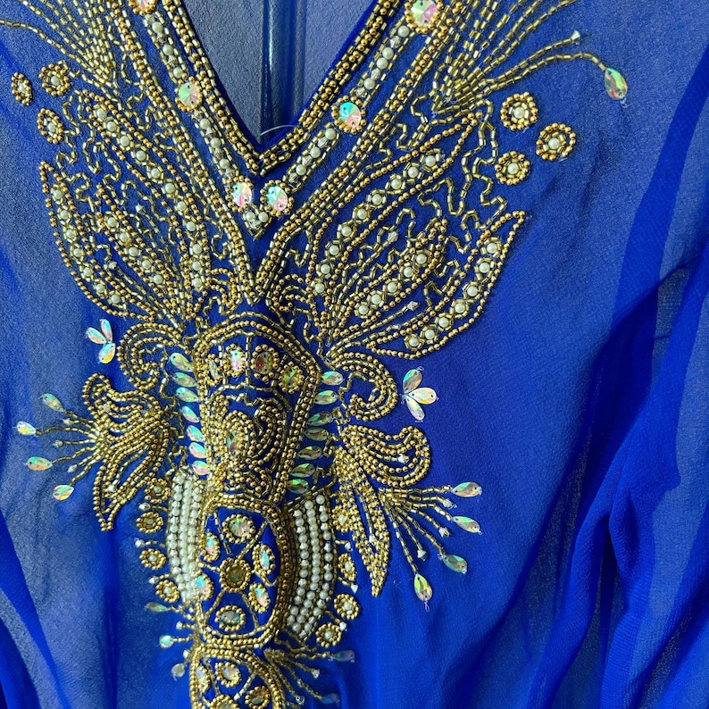 May include: A royal blue sheer top with a gold and white beaded design. The design features intricate floral patterns and sequins.