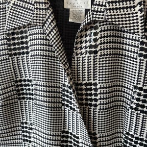 May include: Black and white patterned blouse with a collar and a button-up front. The blouse has a petite size label.