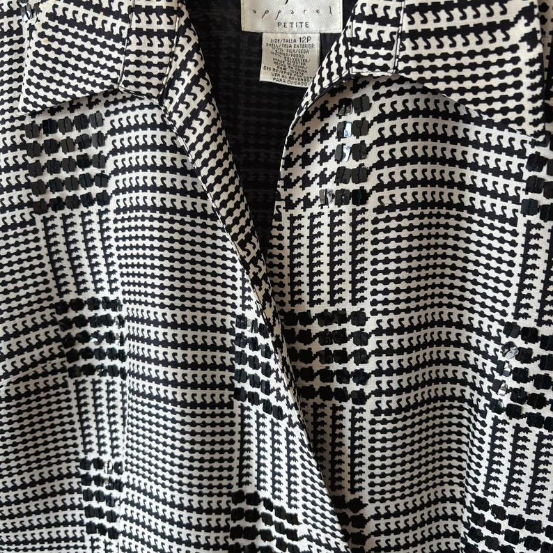 May include: Black and white patterned blouse with a collar and a button-up front. The blouse has a petite size label.