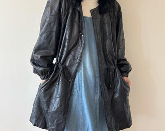 May include: Black leather coat with a quilted pattern and a faux fur-trimmed hood. The coat has a drawstring waist, snap closures, and pockets. The coat is worn over a denim dress.