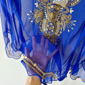 May include: A royal blue sheer fabric with gold and pearl embellishments. The fabric has a scalloped edge and is decorated with a floral design.