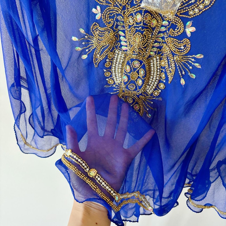 May include: A royal blue sheer fabric with gold and pearl embellishments. The fabric has a scalloped edge and is decorated with a floral design.