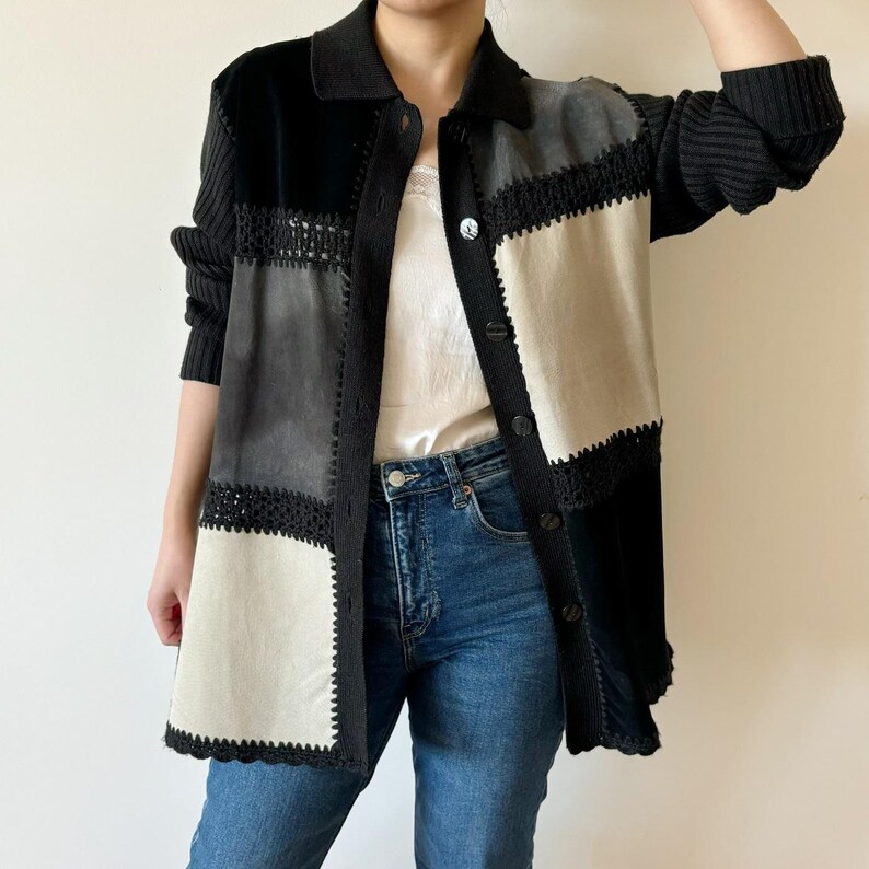 May include: A black and white patchwork cardigan with crocheted trim. The cardigan has a collar and a button closure.