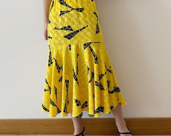 May include: A yellow skirt with a black geometric pattern. The skirt has a flared hem and is knee-length.