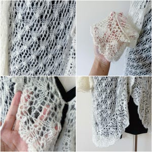 May include: Ivory-colored, open-weave knit shrug. The delicate, lacy pattern is visible in close-up shots, showcasing the intricate design. The shrug features short sleeves and a scalloped edge, offering a lightweight and airy feel.