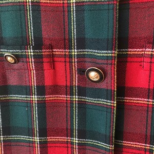 Puede incluir: Tela de cuadros rojos, verdes y blancos con dos botones dorados. Los botones tienen un centro negro y un dise&ntilde;o en relieve.