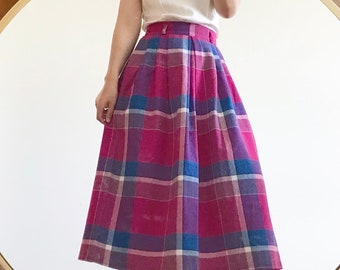 May include: A high-waisted midi skirt with a plaid pattern in shades of pink, purple, blue, and white. The skirt has pleats and a fitted waistband.
