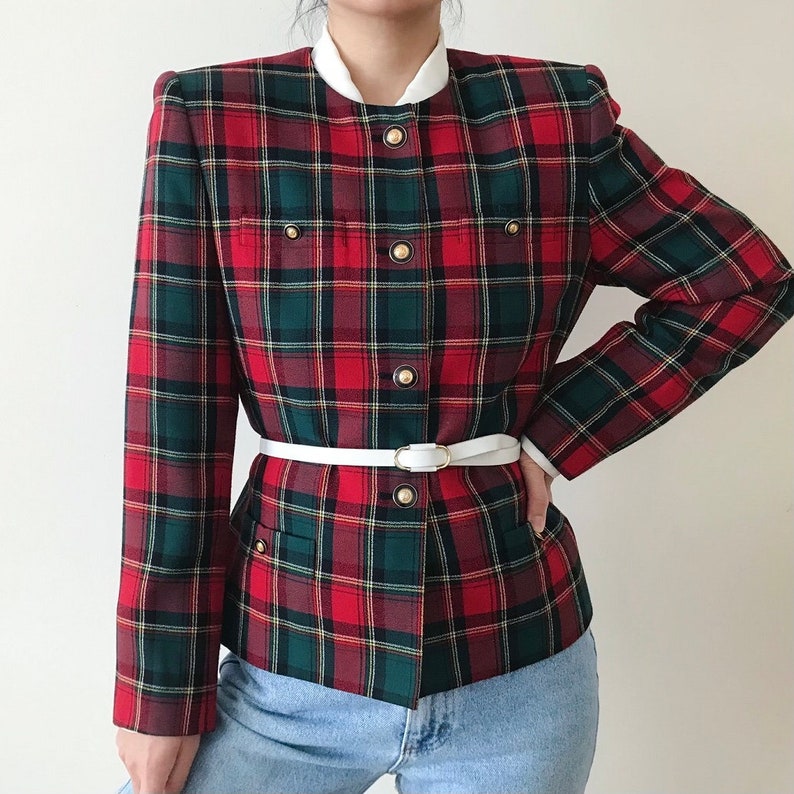 Puede incluir: Una chaqueta de cuadros rojos y verdes con cuello blanco y cintur&oacute;n blanco. La chaqueta tiene botones dorados y dos bolsillos en la parte delantera.