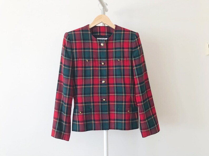 Puede incluir: Una chaqueta de cuadros rojos, verdes y negros con botones dorados. La chaqueta tiene un cuello mandar&iacute;n y cierre de botones en la parte delantera.
